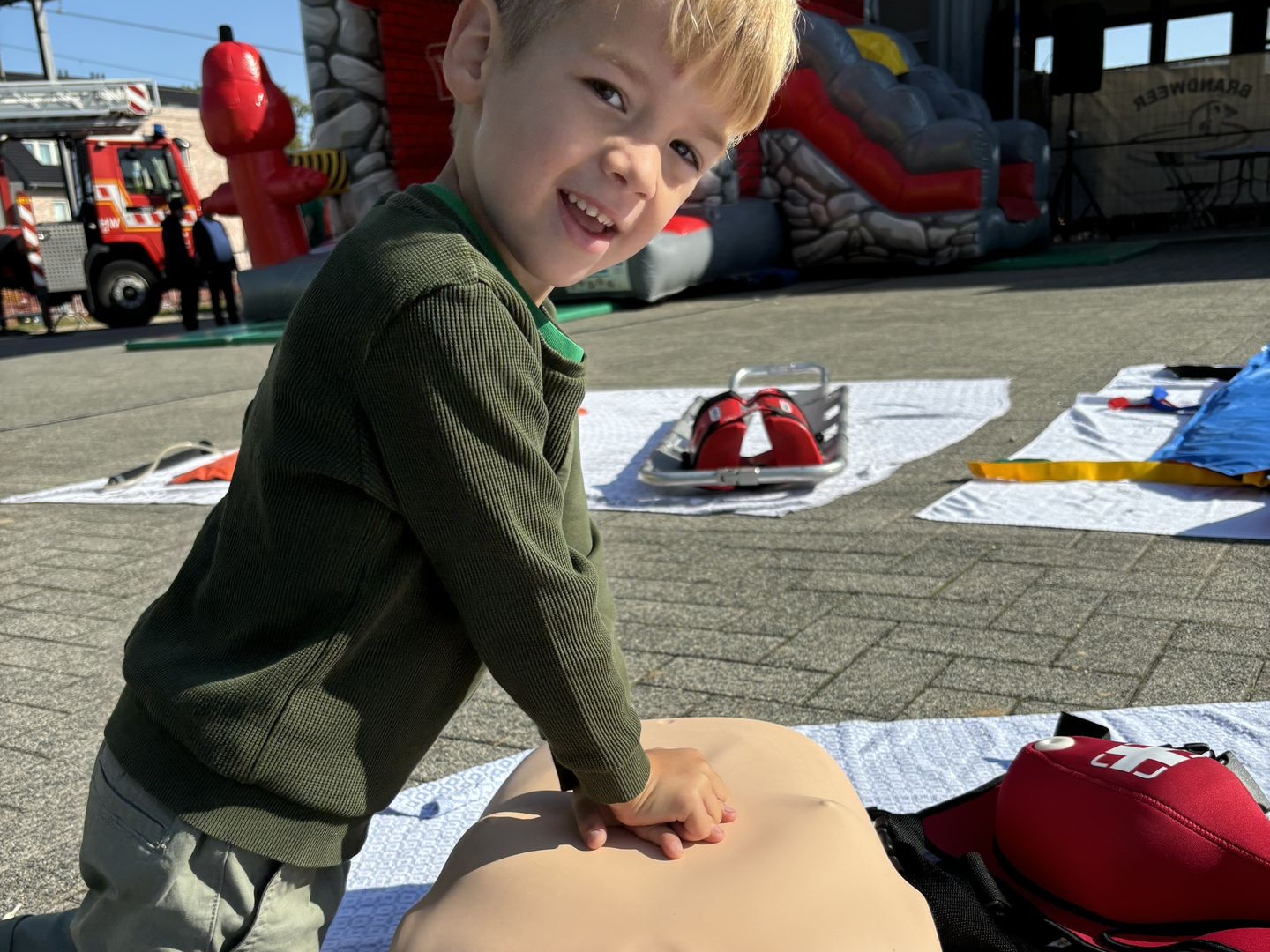 Jong kind die poseert wanneer hij een volwassene reanimatiepop reanimeert